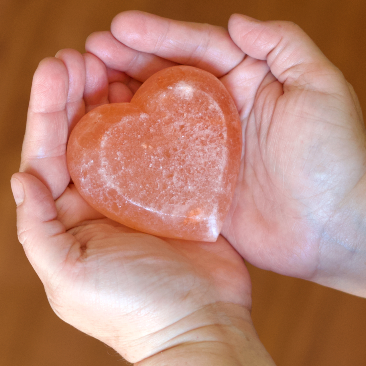 Hands holding a rose quartz heart